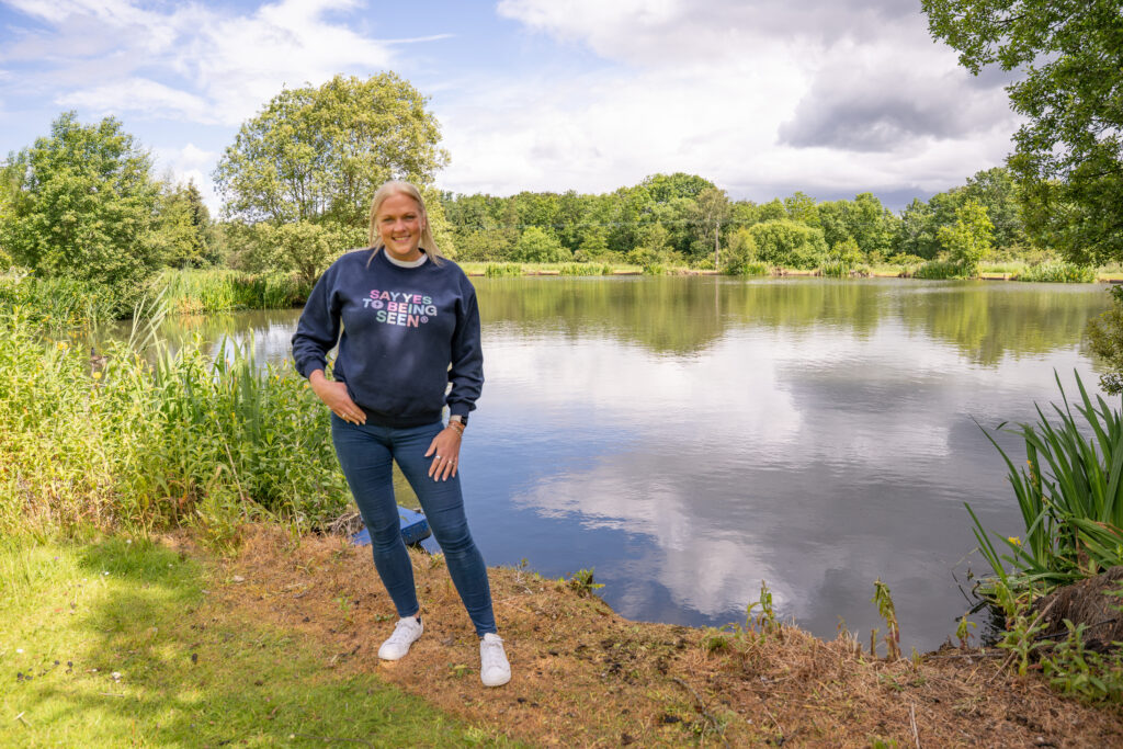 Business Coach Sarah Johnson Photography stood by a lake in jeans and a jumper